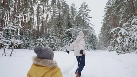 cheerful-woman-and-her-little-son-in-old-wooden-sledge-are-walking-in-forest-in-winter